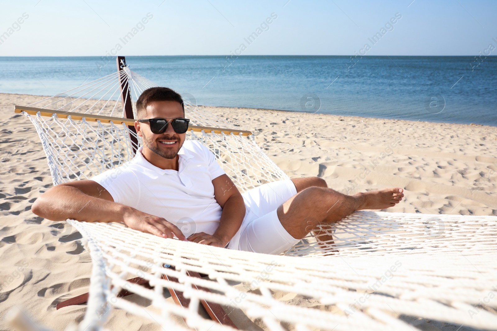 Photo of Young man relaxing in hammock on beach