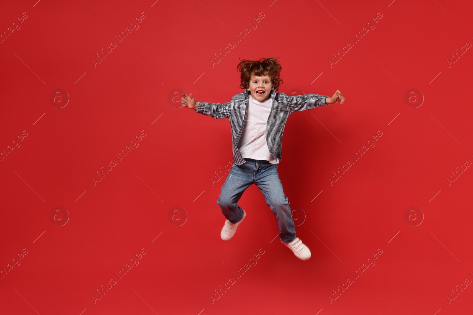 Photo of Happy little boy dancing on red background. Space for text