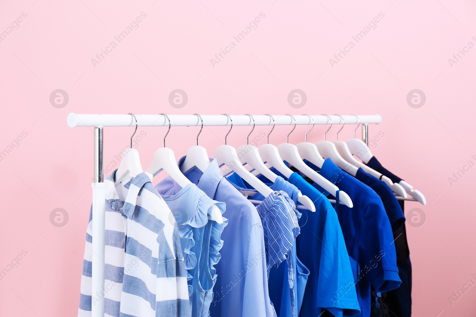 Photo of Rack with bright clothes on color background