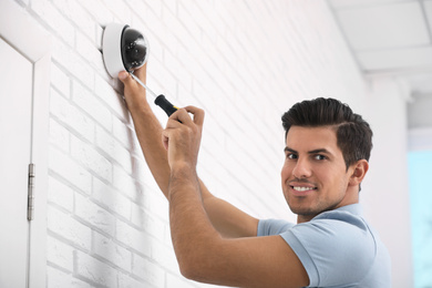 Technician installing CCTV camera on wall indoors