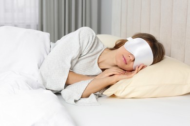 Woman with sleep mask in bed at home