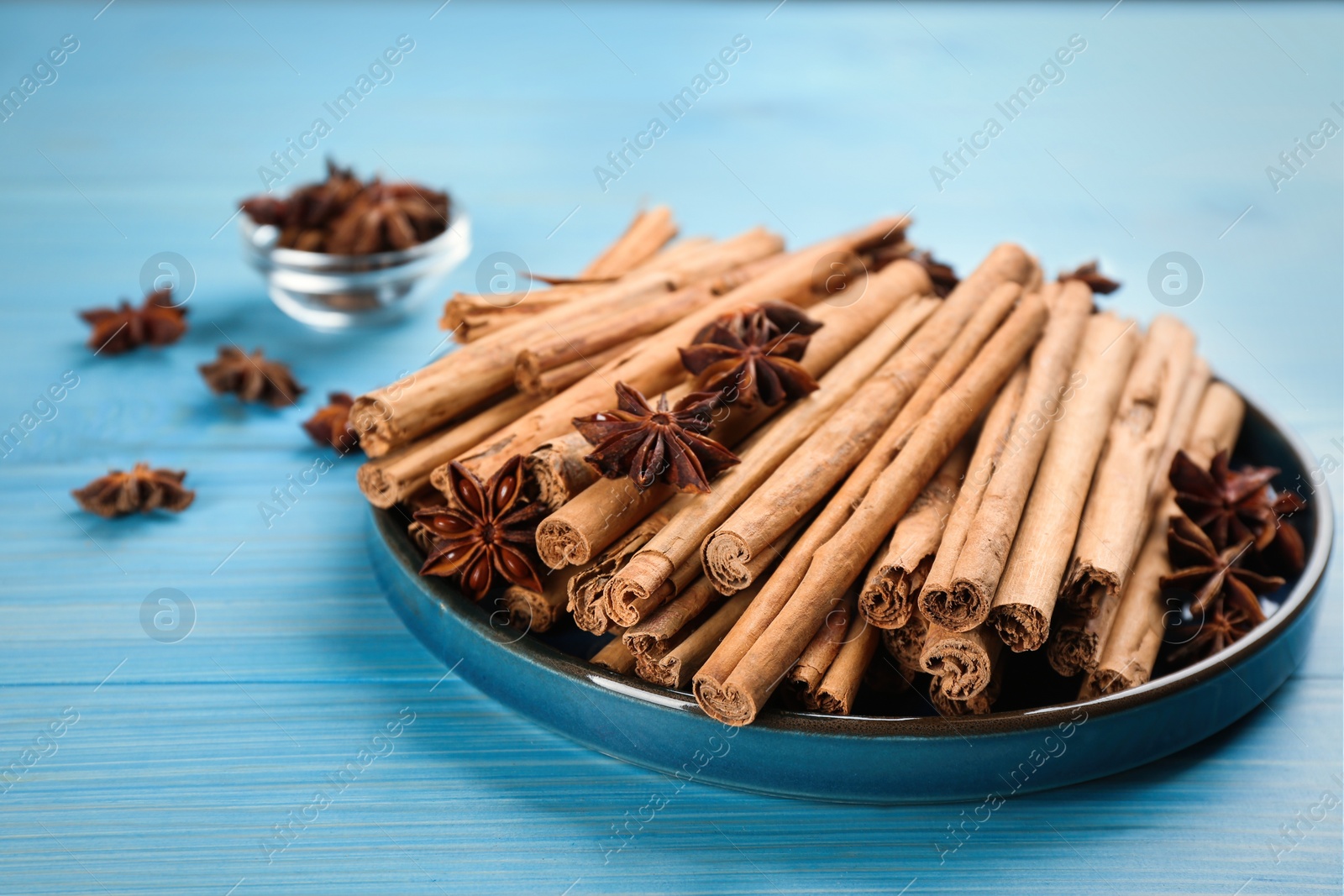 Photo of Aromatic cinnamon sticks and anise on light blue wooden table