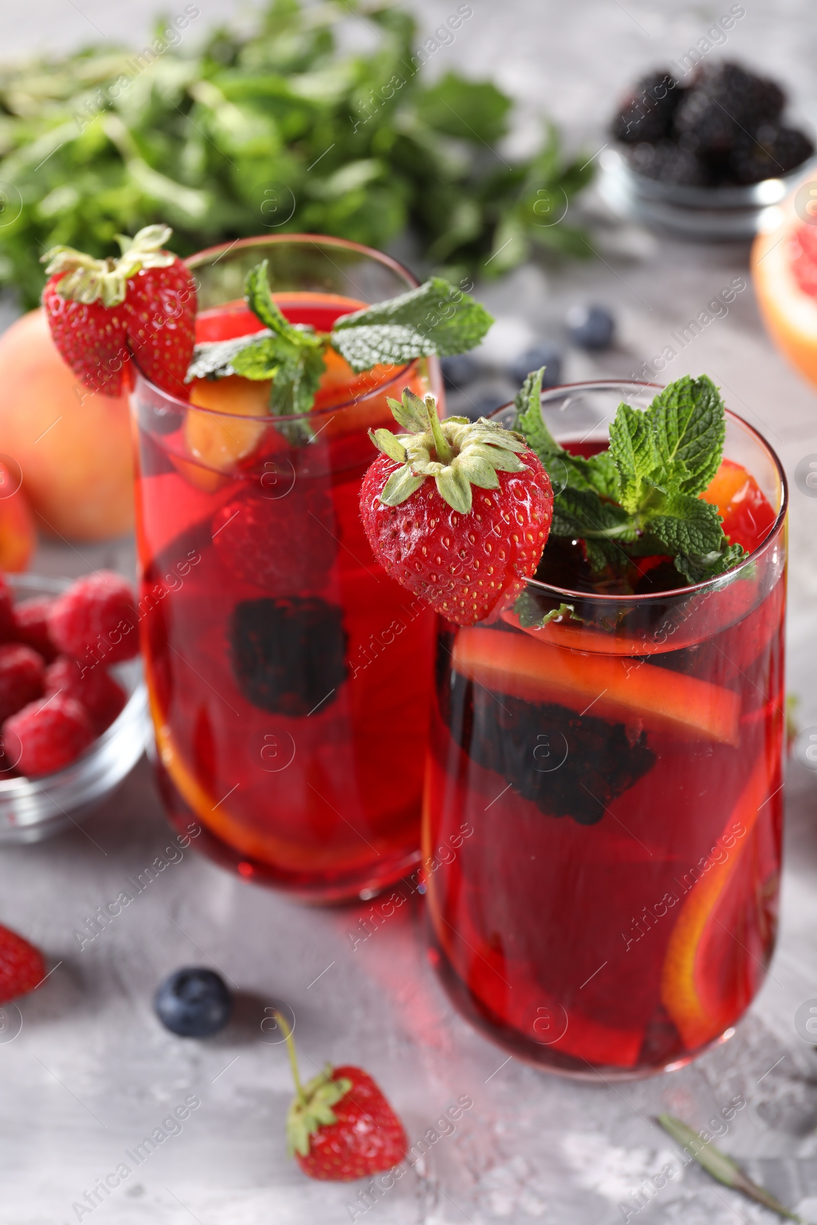 Photo of Delicious refreshing sangria and ingredients on light grey table, closeup