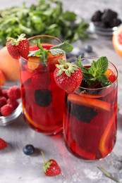 Photo of Delicious refreshing sangria and ingredients on light grey table, closeup