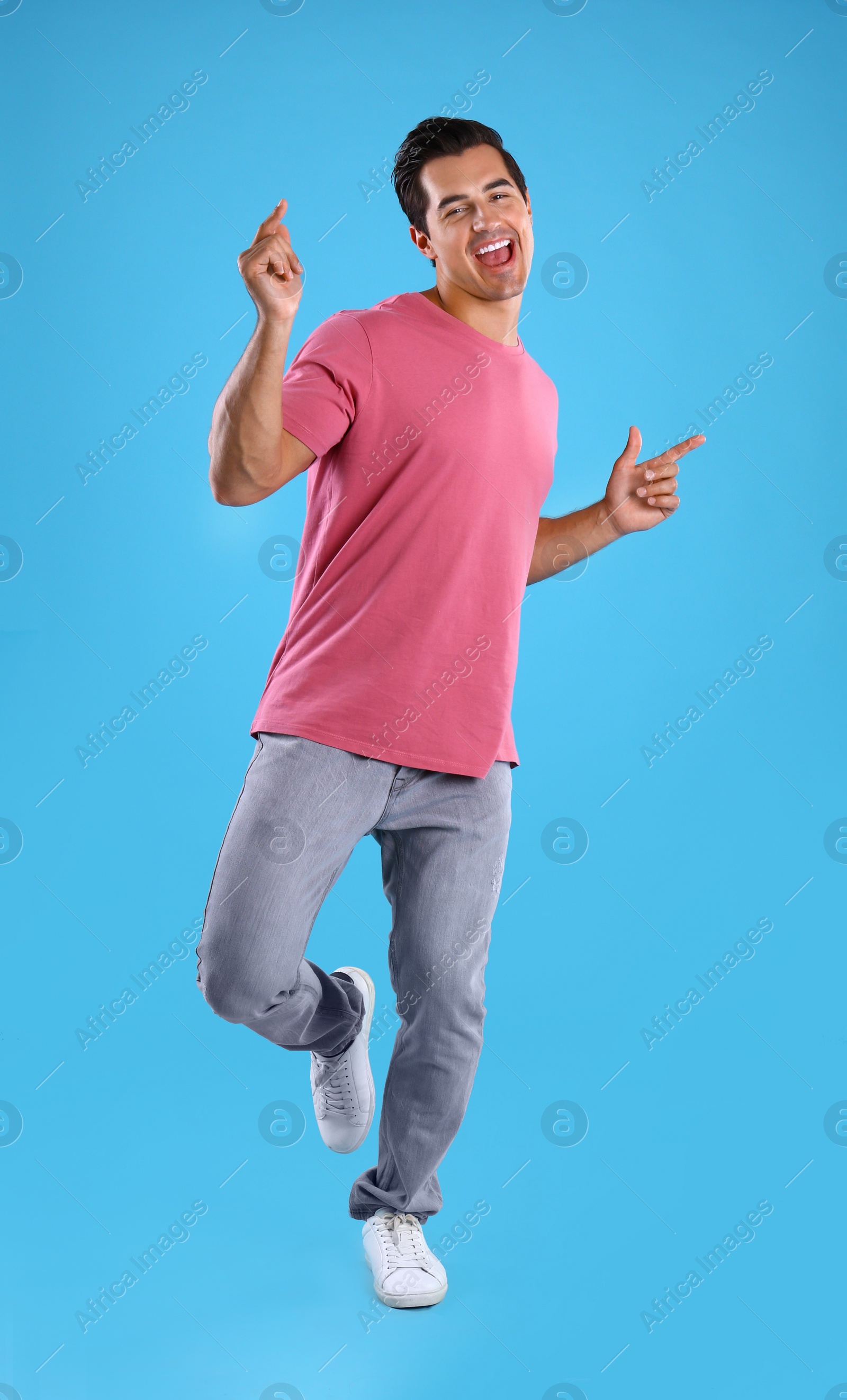 Photo of Handsome young man dancing on blue background