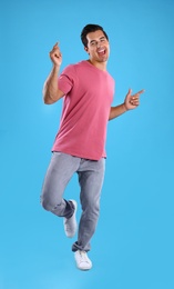 Handsome young man dancing on blue background