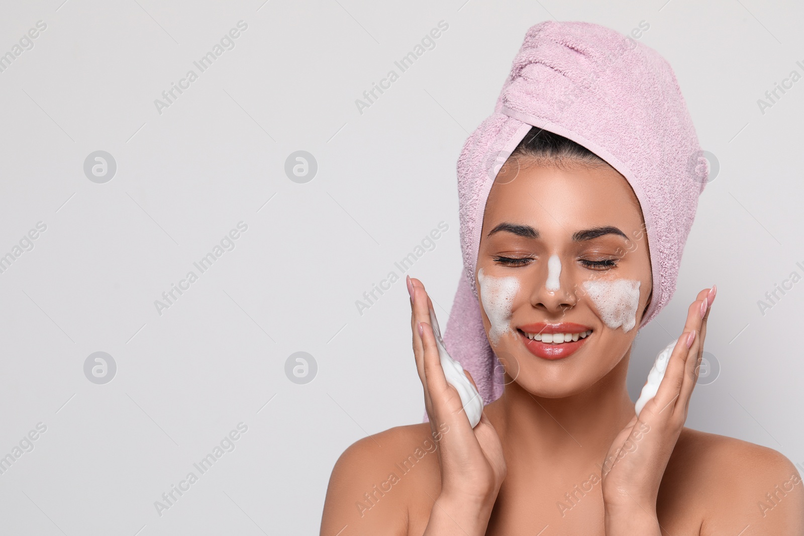 Photo of Beautiful woman applying facial cleansing foam on white background, space for text