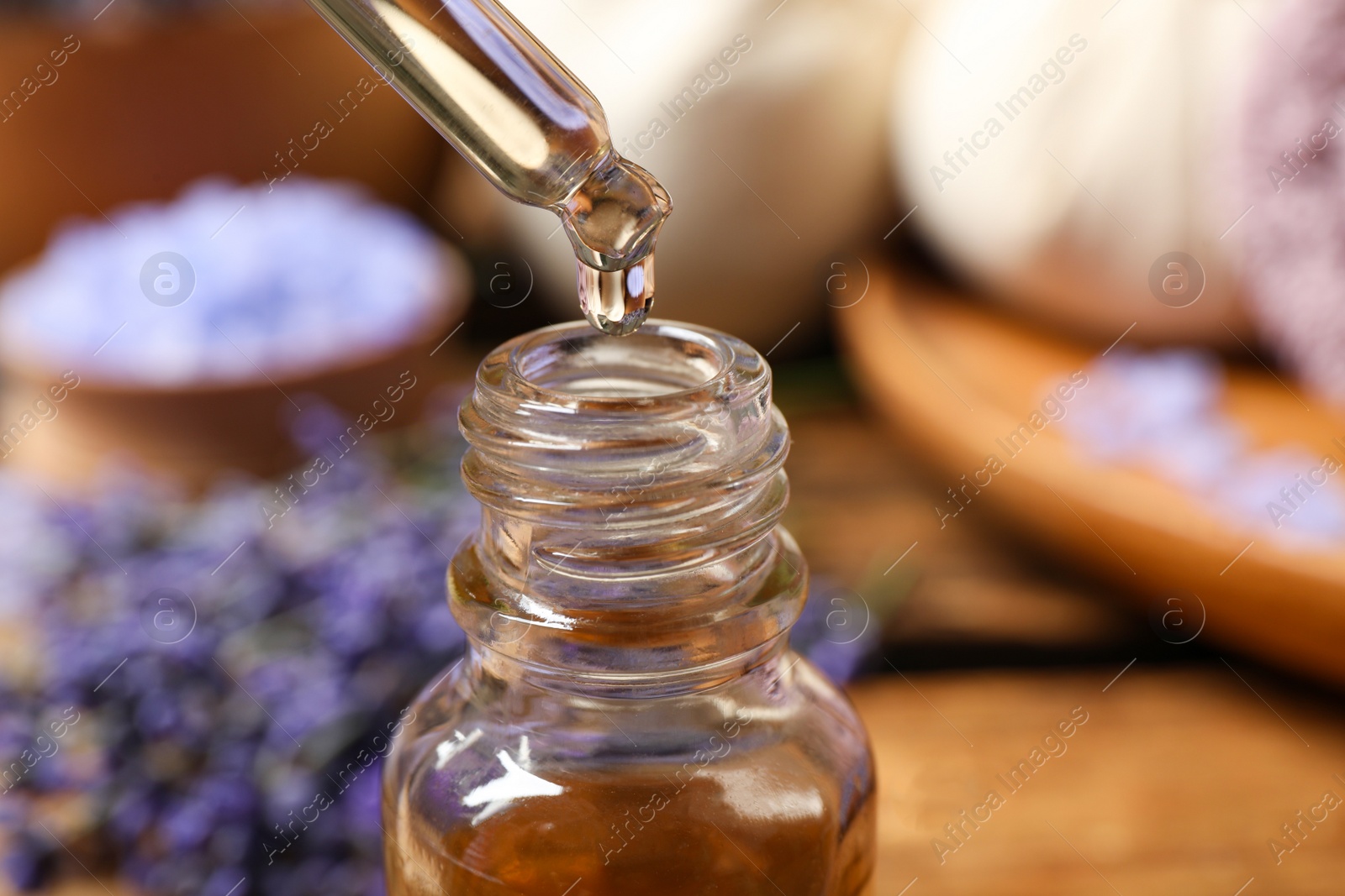 Photo of Dripping lavender essential oil into bottle, closeup