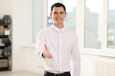 Photo of Happy man welcoming and offering handshake in office