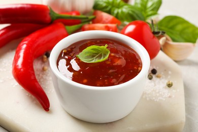 Photo of Spicy chili sauce with basil on light table