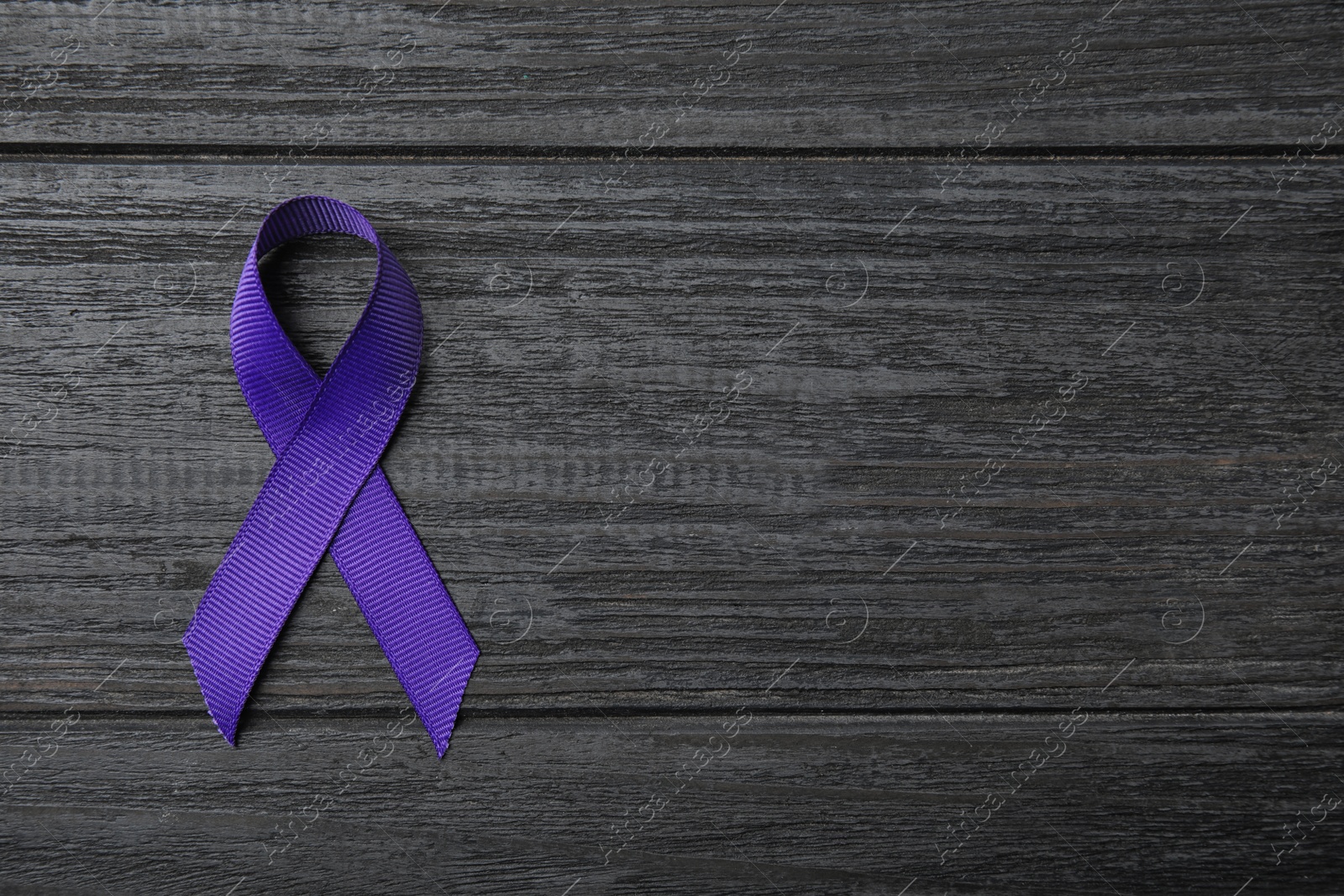 Photo of Purple ribbon on grey wooden background, top view with space for text. Domestic violence awareness