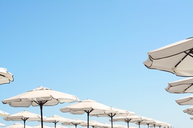 Photo of Beautiful white beach umbrellas against blue sky, space for text