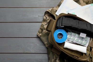 Photo of Military first aid kit and uniform on wooden table, flat lay. Space for text