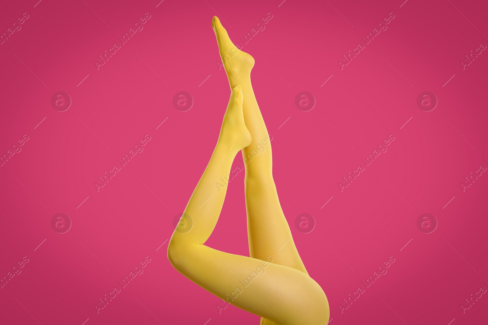 Photo of Woman wearing yellow tights on crimson background, closeup of legs