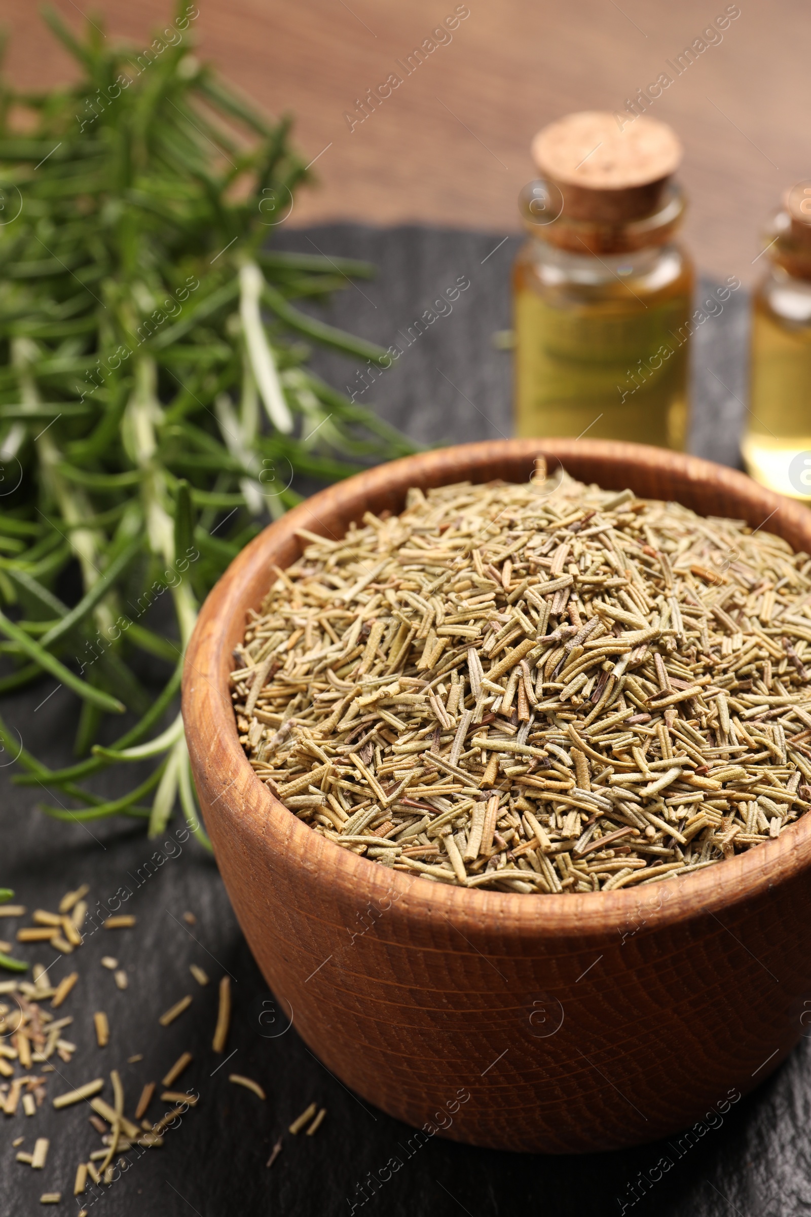 Photo of Essential oil, fresh and dry rosemary on table, closeup