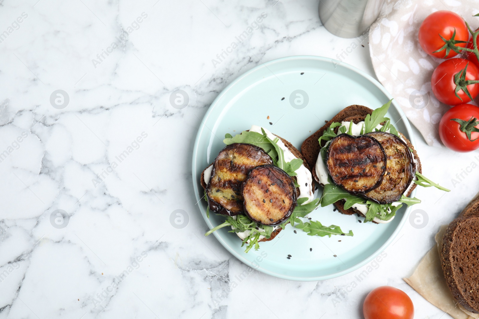 Photo of Delicious eggplant sandwiches served on white marble table, flat lay. Space for text