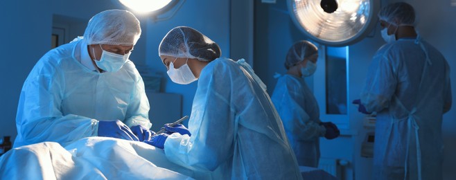 Image of Team of professional doctors performing operation in surgery room. Banner design