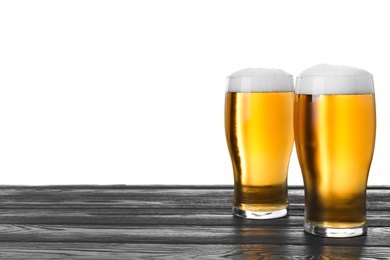 Photo of Glasses of tasty beer on black wooden table against white background