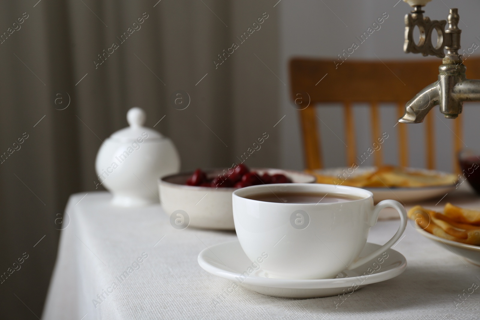 Photo of Vintage samovar, cup of hot drink and snacks served on table indoors. Traditional Russian tea ceremony