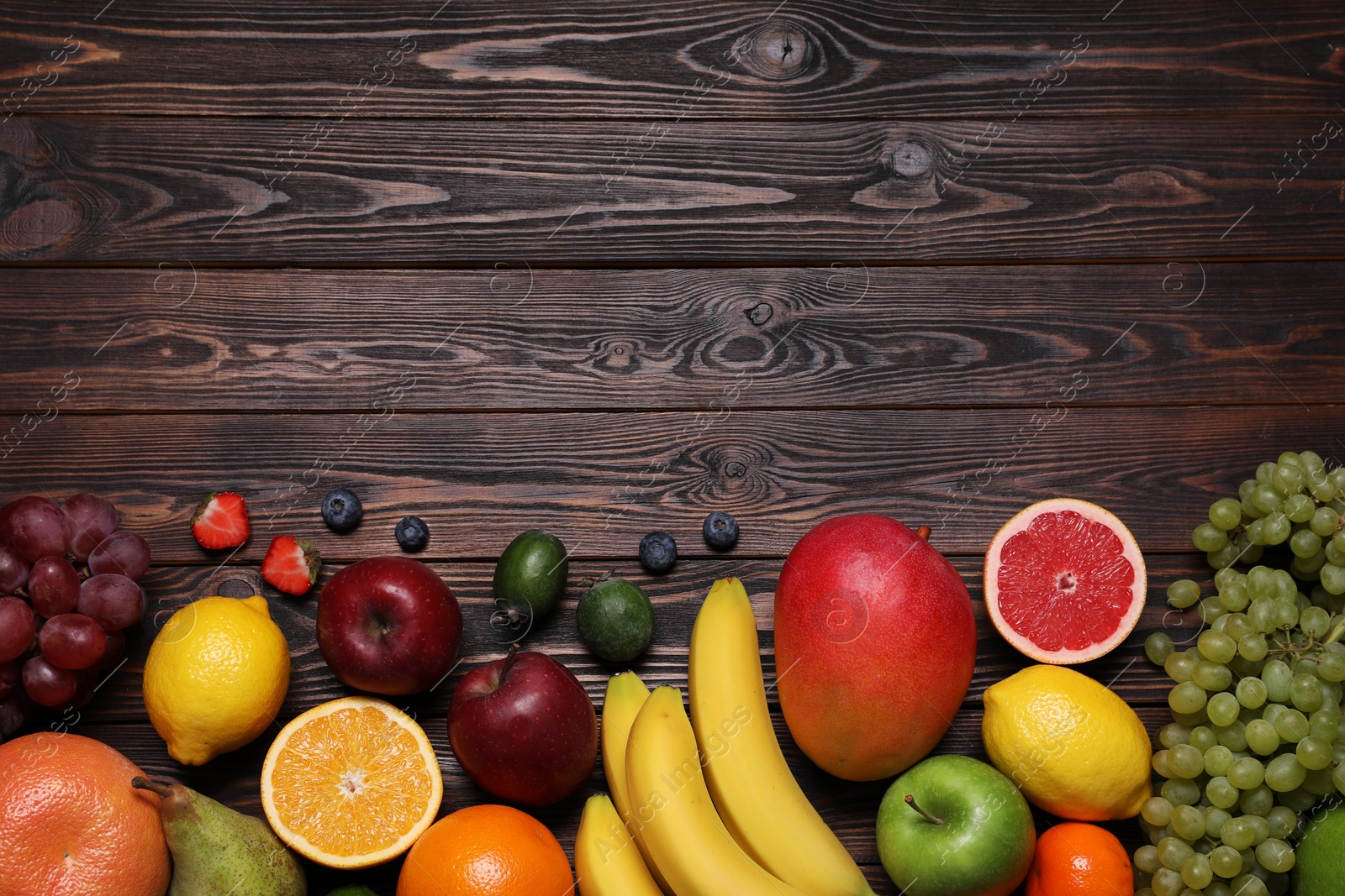 Photo of Different ripe fruits on wooden table, top view. Space for text