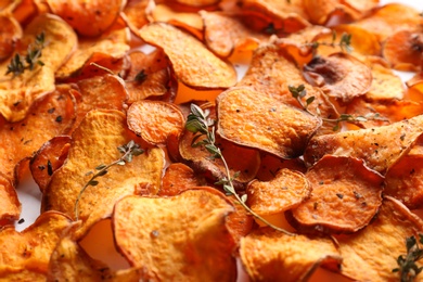 Photo of Sweet potato chips with herbs as background, closeup