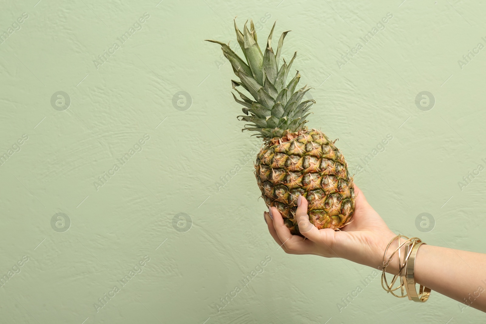 Photo of Woman holding pineapple on color background, closeup