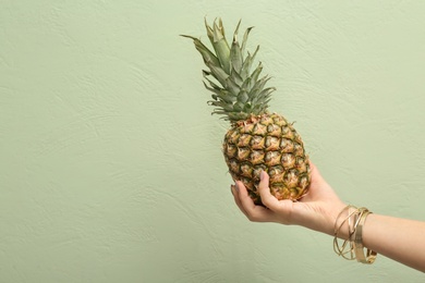 Photo of Woman holding pineapple on color background, closeup