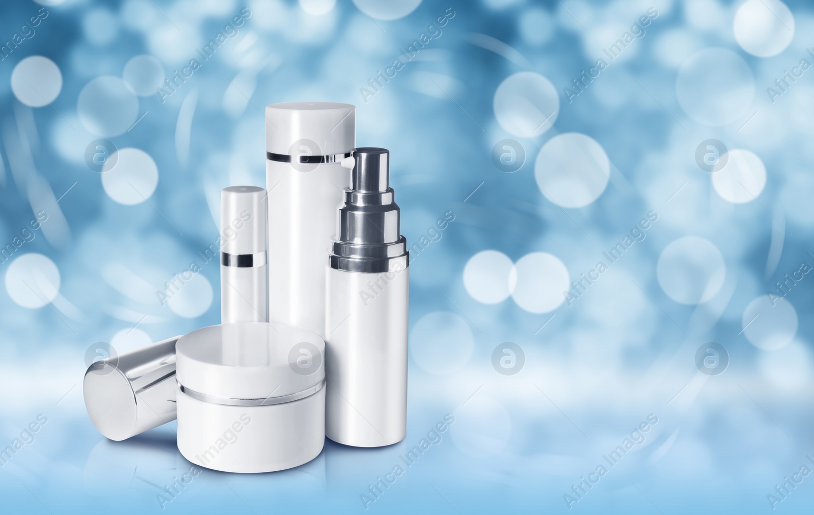 Image of Different cosmetic products on blue background with bokeh effect, space for text. Winter skin care