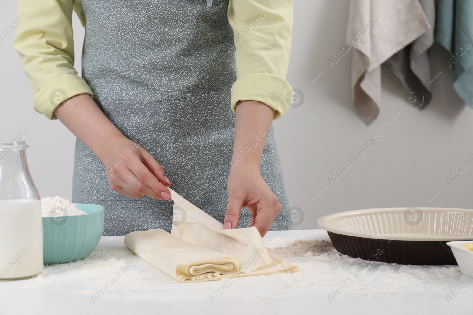 Photo of Making tasty baklava. Woman with dough at table, closeup and space for text