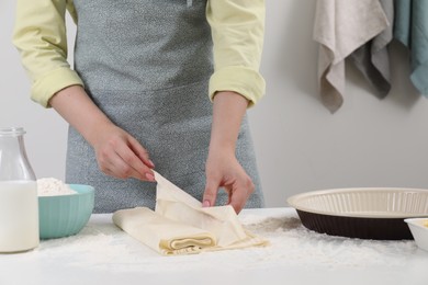 Photo of Making tasty baklava. Woman with dough at table, closeup and space for text
