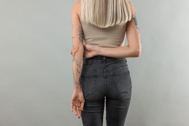 Woman with cool tattoos on gray background, closeup