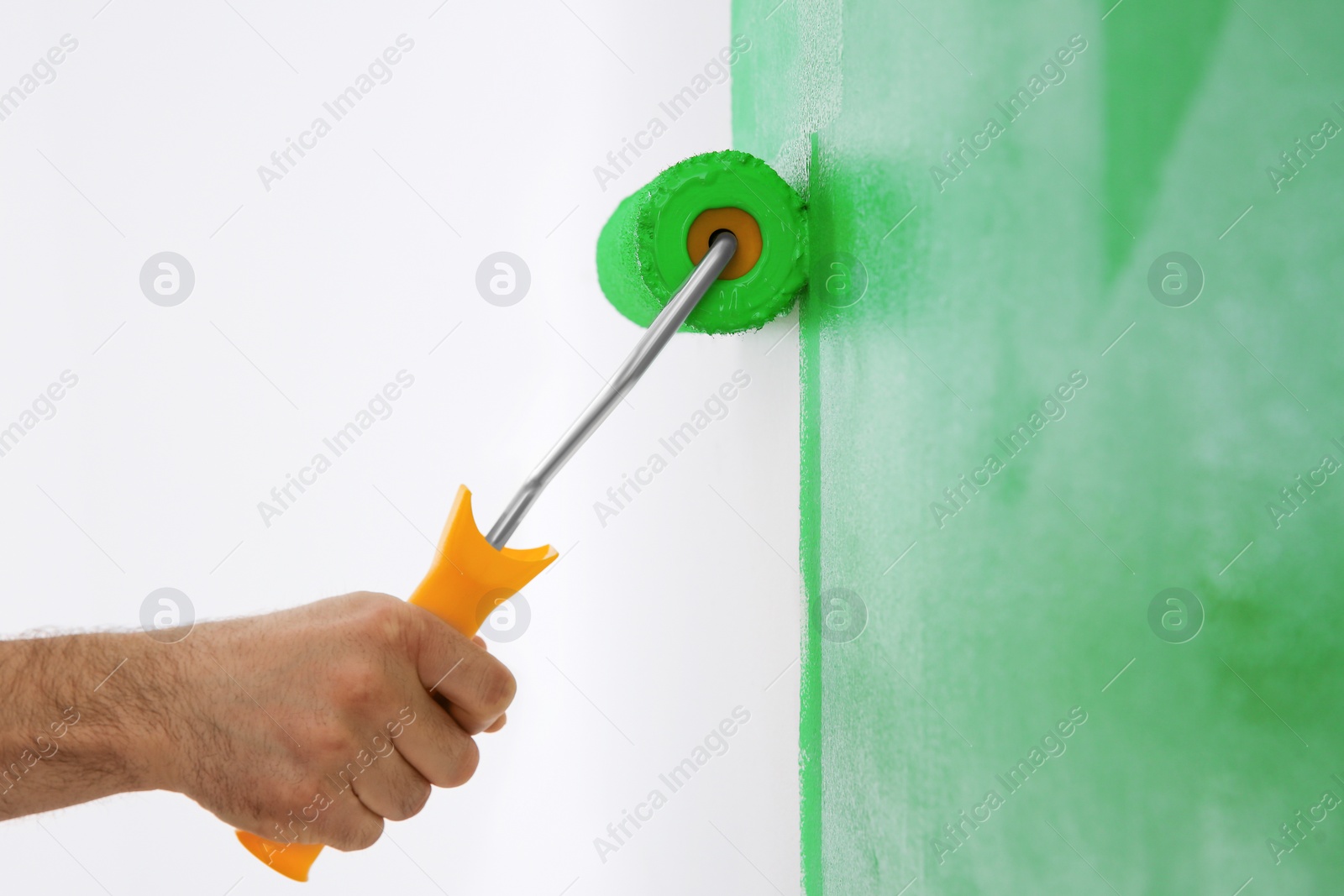 Photo of Man painting white wall with green dye, closeup. Interior renovation