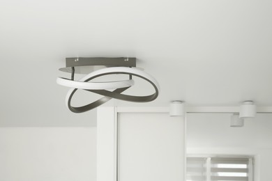 Photo of Stylish lamp on white ceiling. Space for text