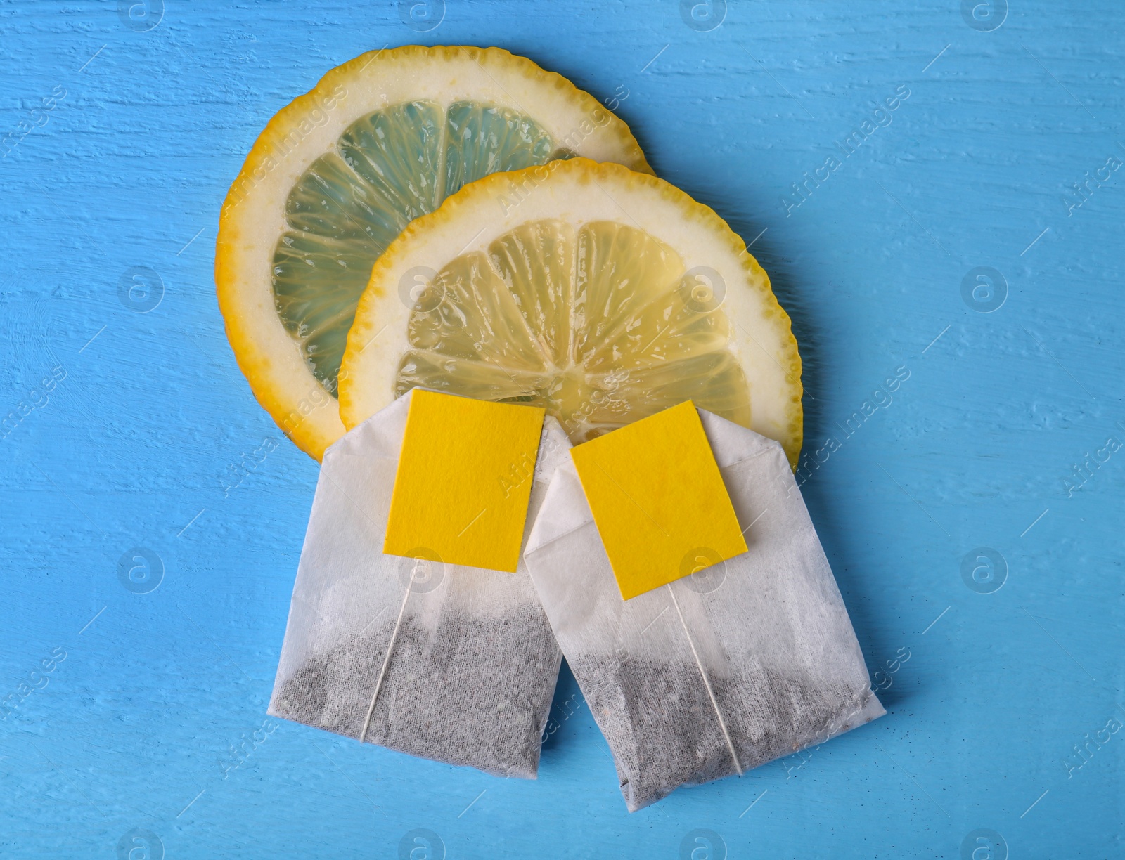 Photo of Tea bags and lemon on light blue wooden table, flat lay