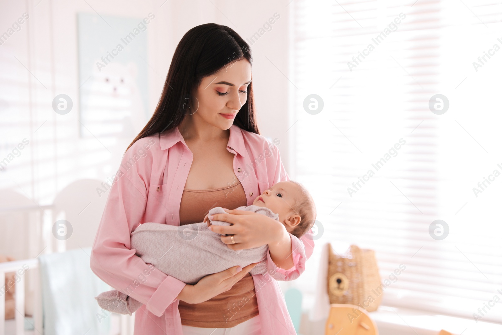 Photo of Young woman with her cute baby at home, space for text