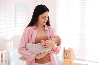 Young woman with her cute baby at home, space for text