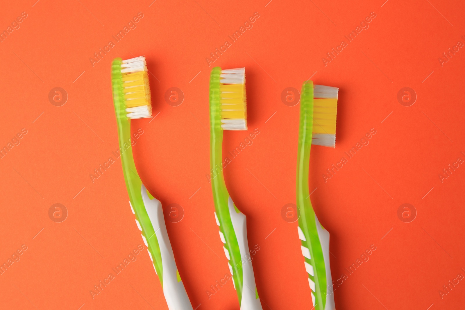 Photo of New toothbrushes on orange background, flat lay