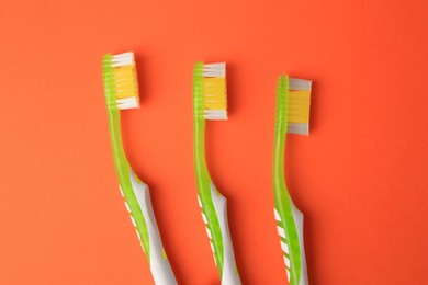 Photo of New toothbrushes on orange background, flat lay