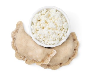 Photo of Raw dumplings (varenyky) and bowl with cottage cheese on white background, top view