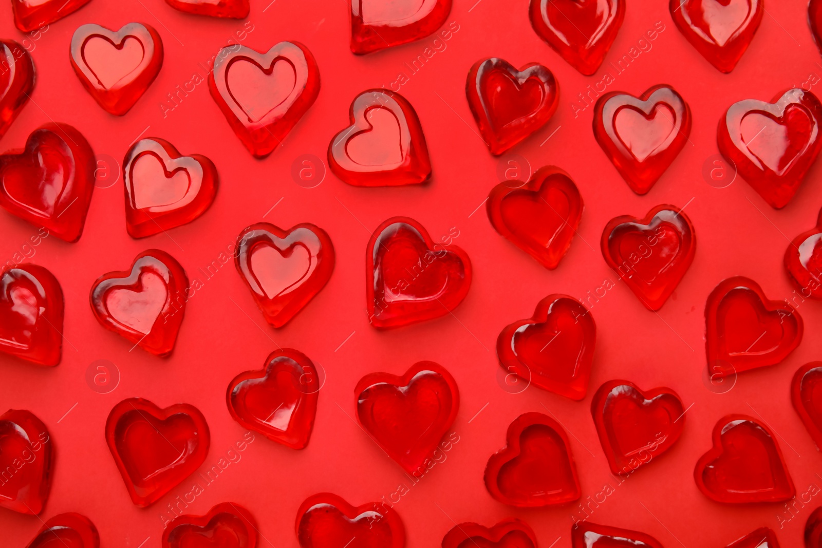 Photo of Many heart shaped jelly candies on red background, flat lay