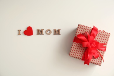 Photo of Flat lay composition with phrase I LOVE MOM and gift box for Mother's Day on light background