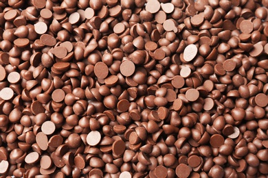 Photo of Many delicious milk chocolate chips as background