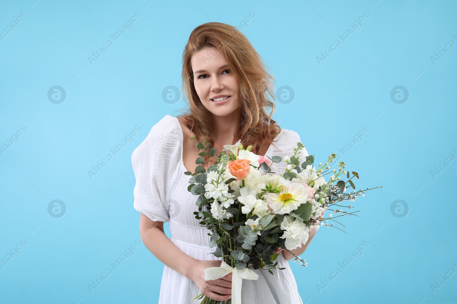 Photo of Beautiful woman with bouquet of flowers on light blue background