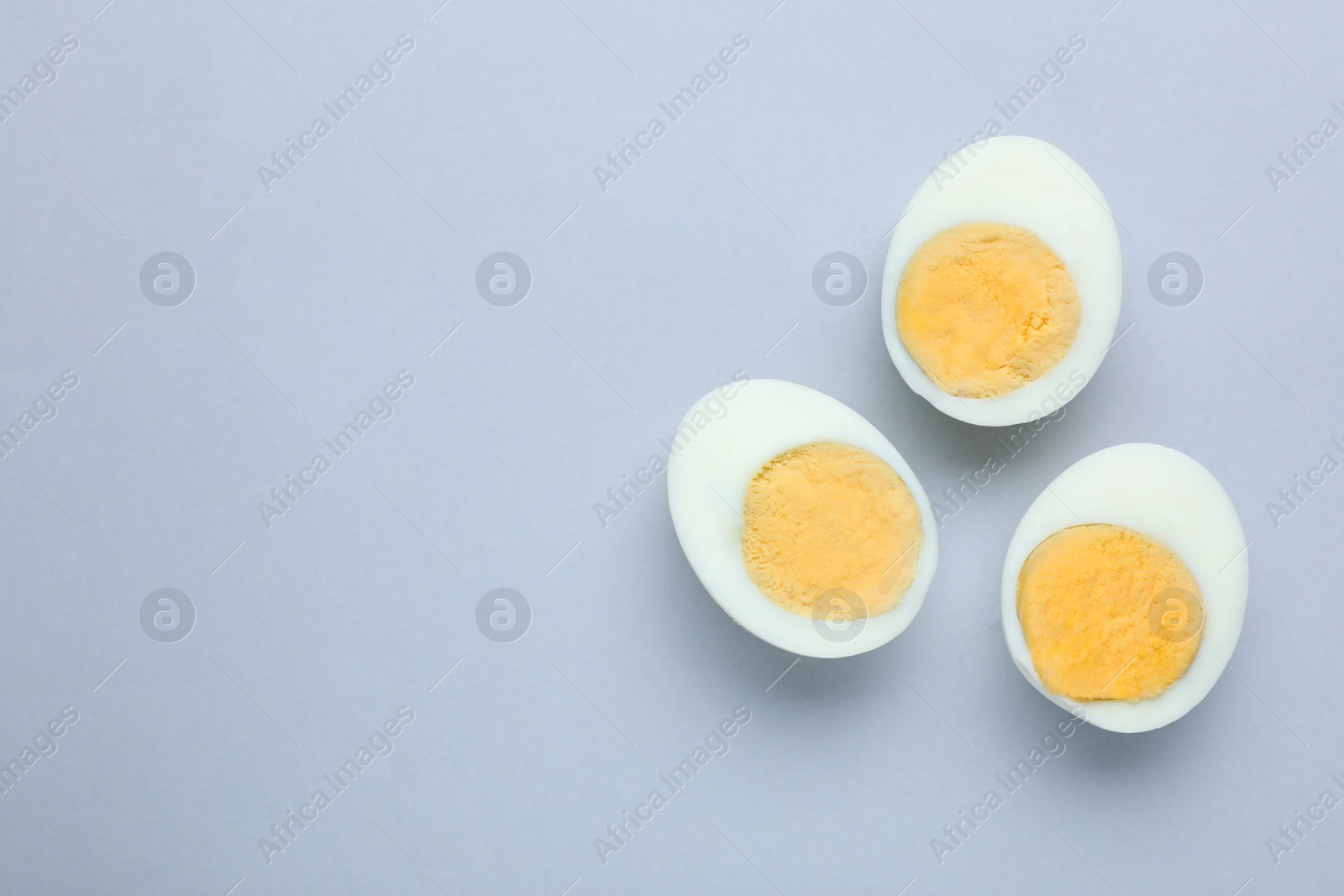 Photo of Cut fresh hard boiled eggs on grey background, flat lay. Space for text