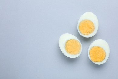 Cut fresh hard boiled eggs on grey background, flat lay. Space for text