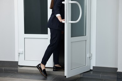 Photo of Woman in stylish suit leaving or entering office building, closeup