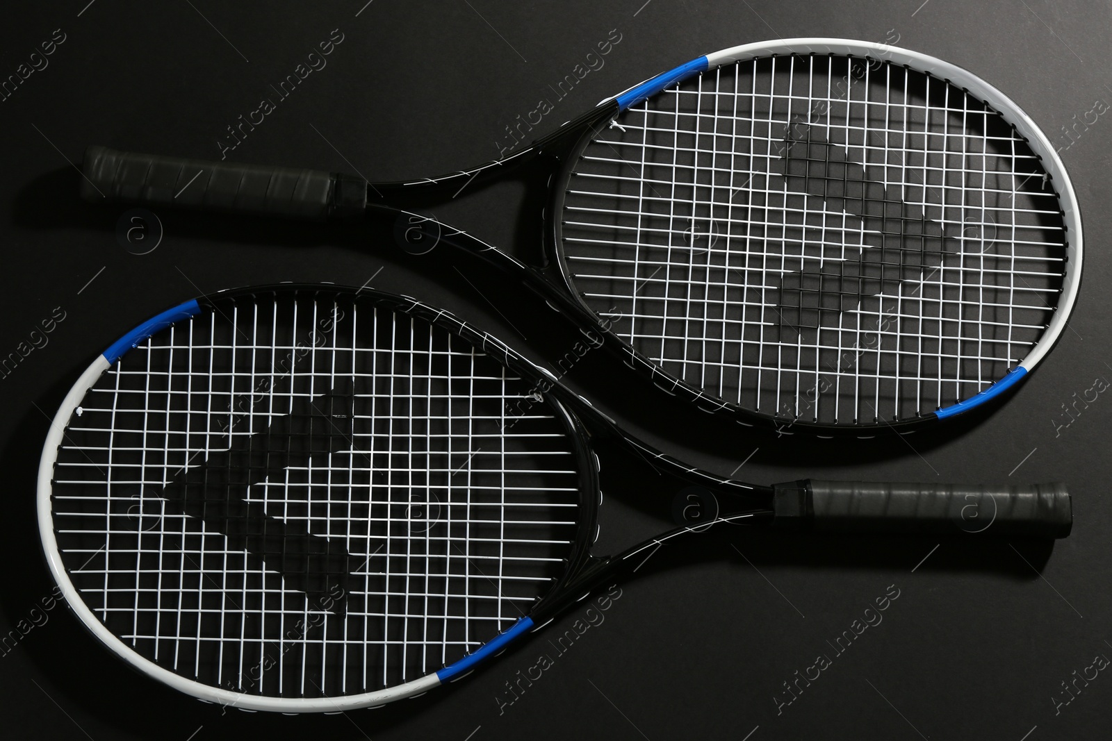 Photo of Tennis rackets on black background, flat lay. Sports equipment