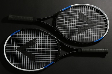 Photo of Tennis rackets on black background, flat lay. Sports equipment