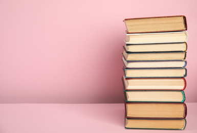 Photo of Stack of hardcover books on pink background. Space for text