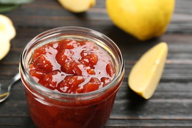 Delicious quince jam and fruits on black wooden table, closeup